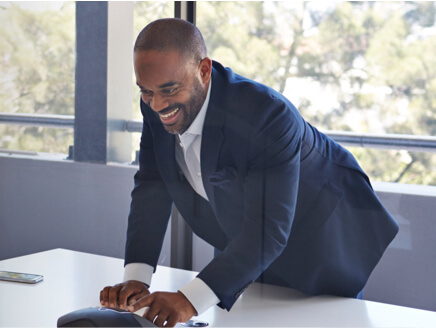 Man leaning over a conference phone, engaged in a phone conversation.